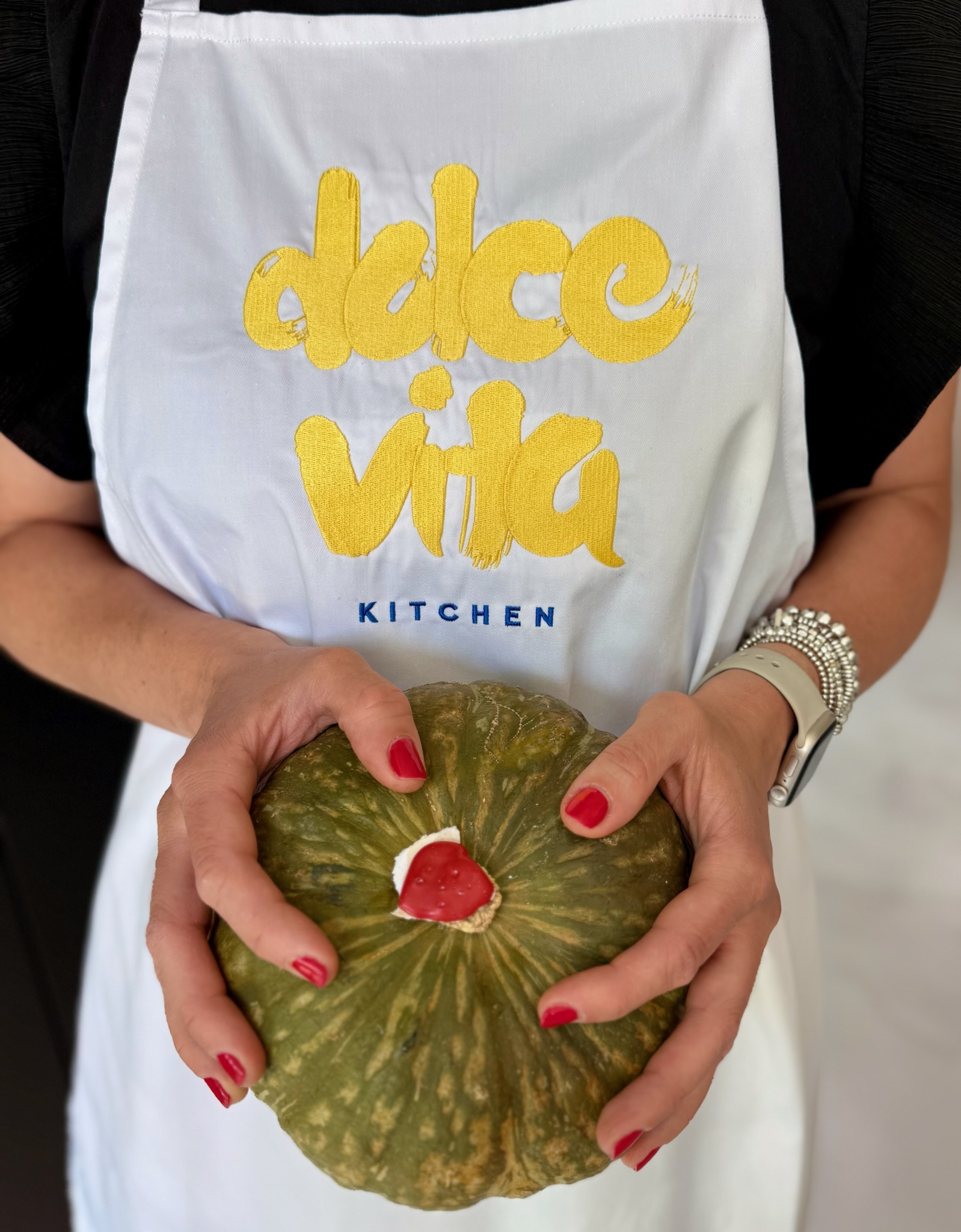 Ilaria holding a delica pumpkin in her Dolce Vita Kitchen apron