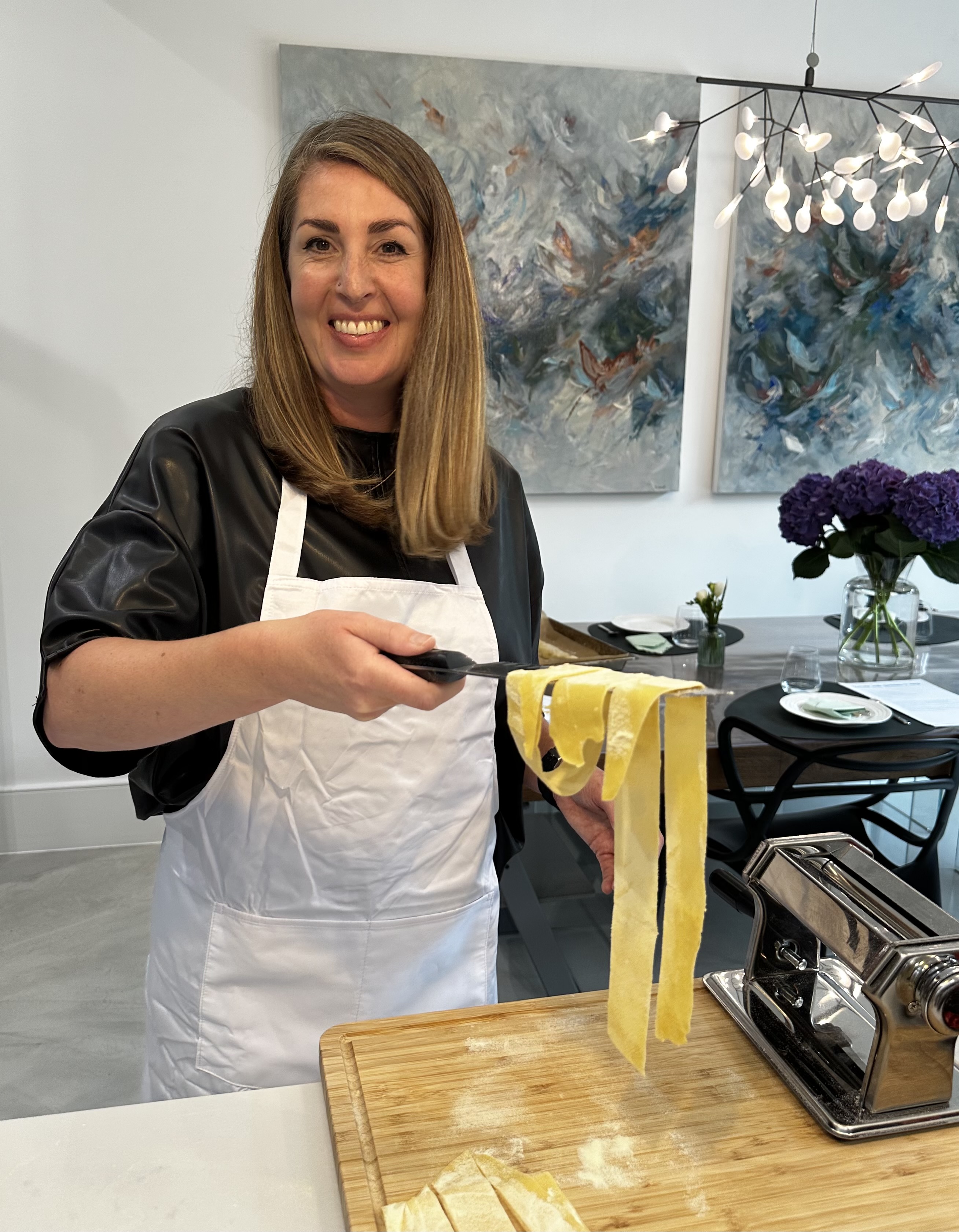 Guest lifting fresh tagliatelle from the pasta machine